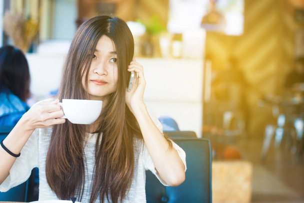 Student women use smartphone in coffee at library of university - 写真・画像