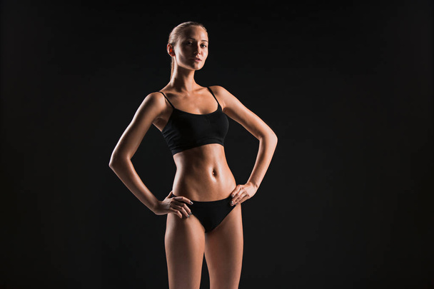 Muscular young woman athlete on black - Foto, imagen