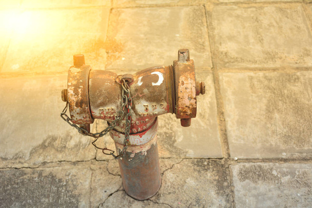 die rostige alte Wasserleitung aus Metall in der Öffentlichkeit unter dem Sonnenlicht und  - Foto, Bild