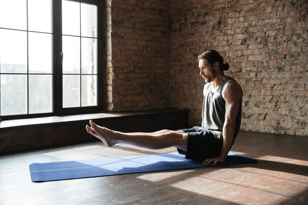 Concentrated strong sportsman in gym make yoga sport exercises - Fotó, kép