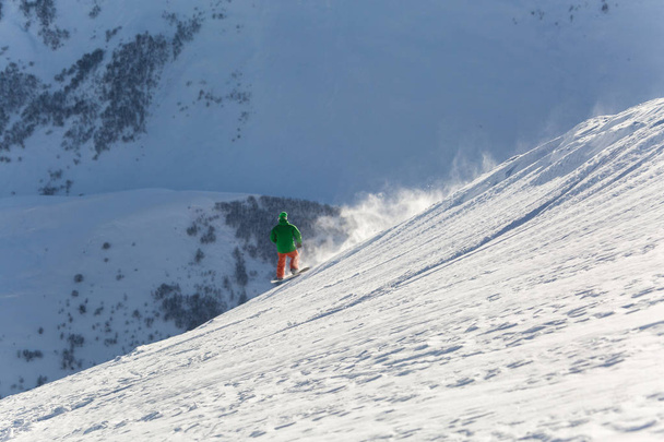 snowboarder snowboard en nieve blanca fresca con pista de esquí en el soleado día de invierno
 - Foto, imagen