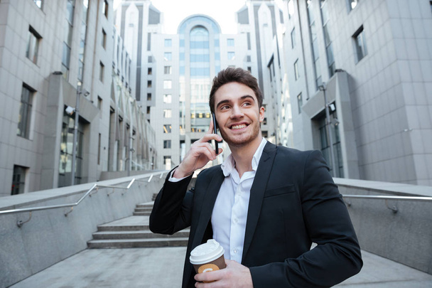 Businessman holding coffee and phone - Zdjęcie, obraz