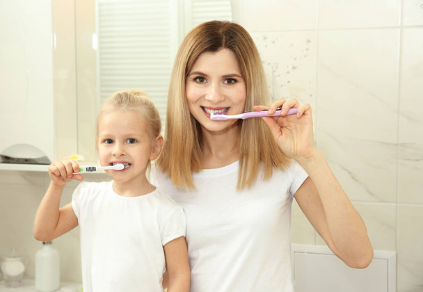 little girl with mother brushing teeth  - Foto, Imagen