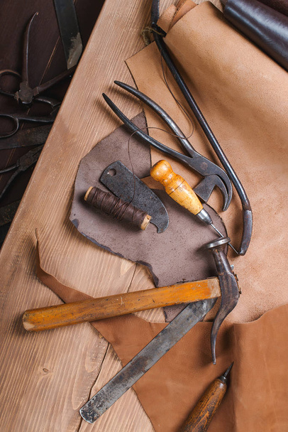 De hulpmiddelen van de schoenmaker in workshop over de houten tafel. Bovenaanzicht. - Foto, afbeelding