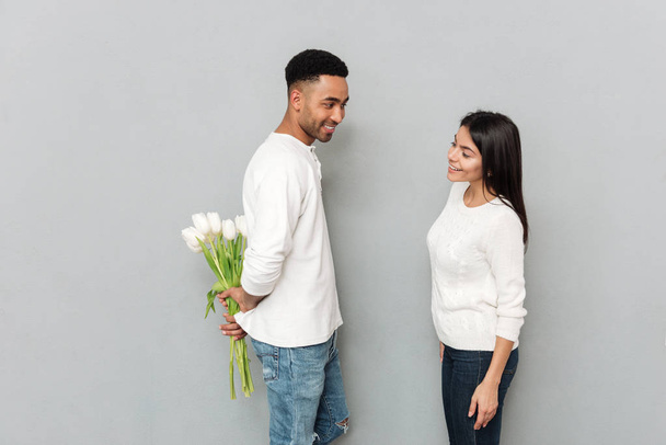 Cheerful man over grey wall with flowers for his lady - Fotoğraf, Görsel