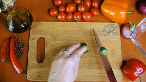 Una donna sta tagliando un cetriolo sul tavolo della cucina
. - Filmati, video