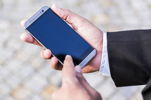 Man in black suit holds mobile phone in his hand - Foto, imagen