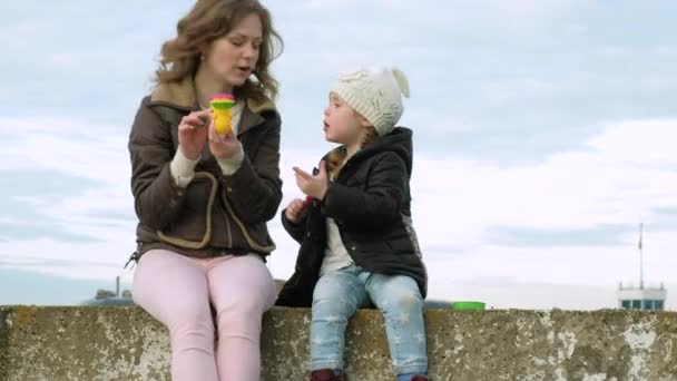 Mutter und Tochter pusten Seifenblasen im Garten - Filmmaterial, Video