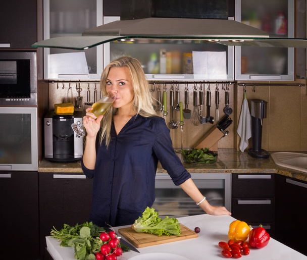 blond young woman cooking salad in kitchen - Fotografie, Obrázek