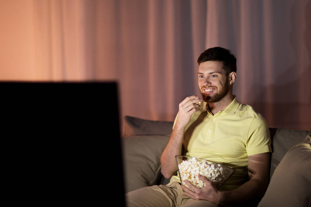 happy man with popcorn watching tv at night - Photo, Image