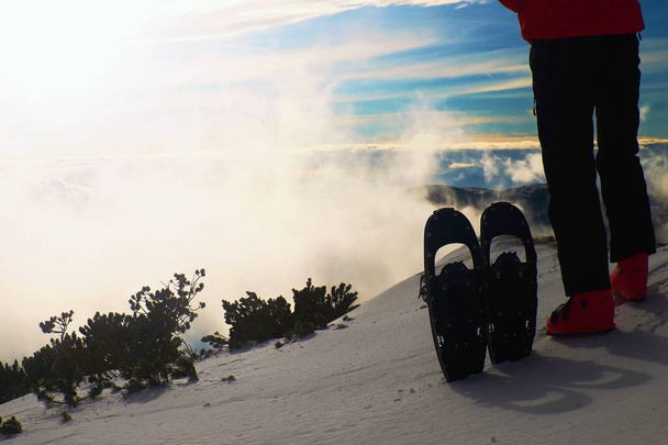 Skifahrer in roter Winterjacke mit lustigen Schneeschuhen bleiben in den Bergen im Schnee. - Foto, Bild