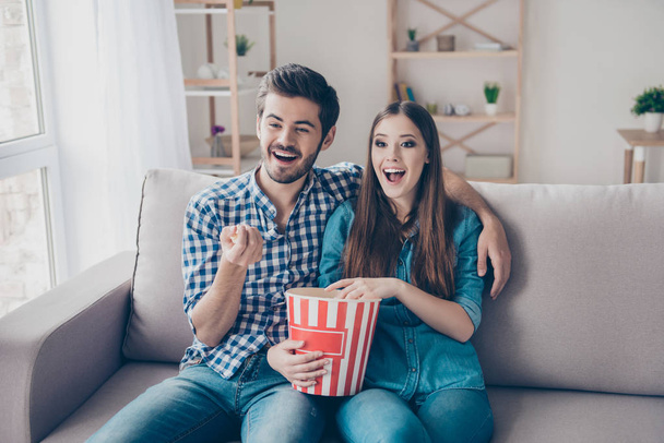 Young beautiful couple is watching movie indoors at home, eating - Zdjęcie, obraz