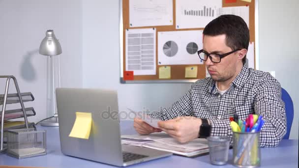 Főnök ül az asztalon, ahol a laptop állványok dokumentumok ellenőrzése - Felvétel, videó