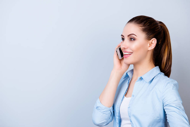 Pretty young smiling woman in blue shirt talking on mobilephone  - Foto, Imagem