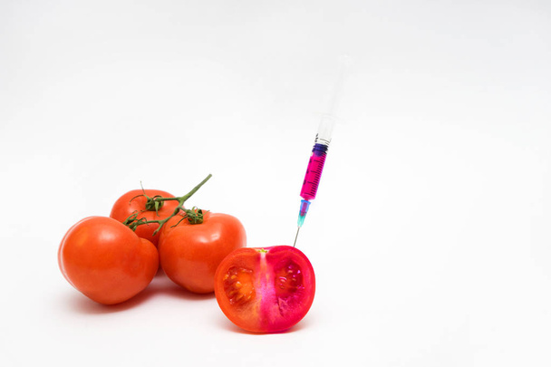 Koncept GMO na bílém pozadí s injekční stříkačky a rajčaty. - Fotografie, Obrázek