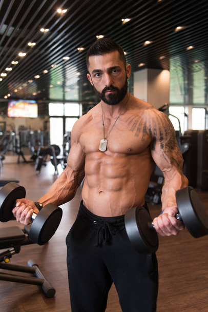 Bodybuilder Exercising Biceps With Dumbbells - Фото, изображение