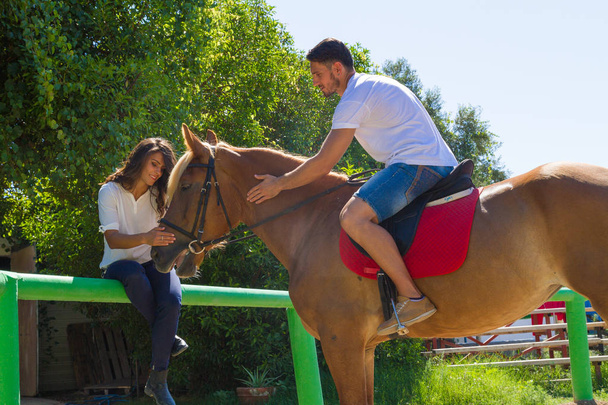 Young couple and their brown-blond horse in the training arena. - Photo, Image