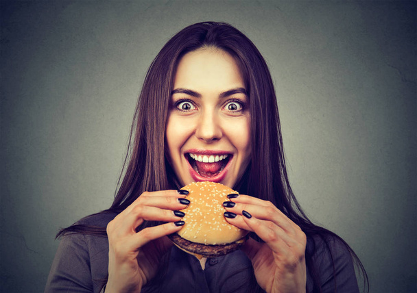 Fast food is my favorite. Woman eating a hamburger enjoying the taste  - Фото, зображення