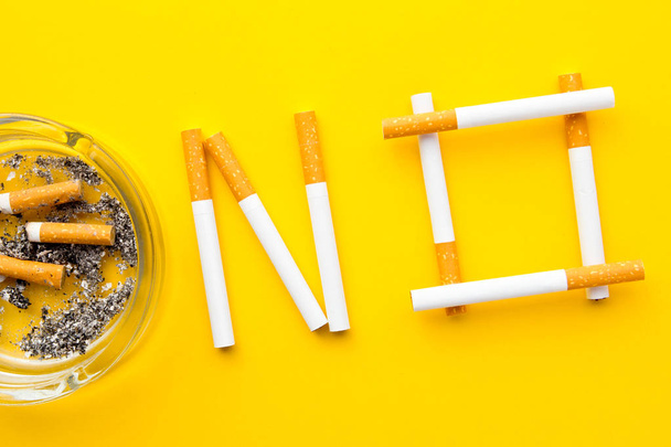Raucherentwöhnung - nein in Zigaretten mit Aschenbecher auf gelbem Hintergrund - Foto, Bild