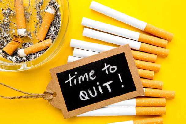 Tupakointi - aika lopettaa - savukkeiden, tuhkakupin ja käsin kirjoitetun liitutaulun kanssa keltaisella pohjalla
 - Valokuva, kuva