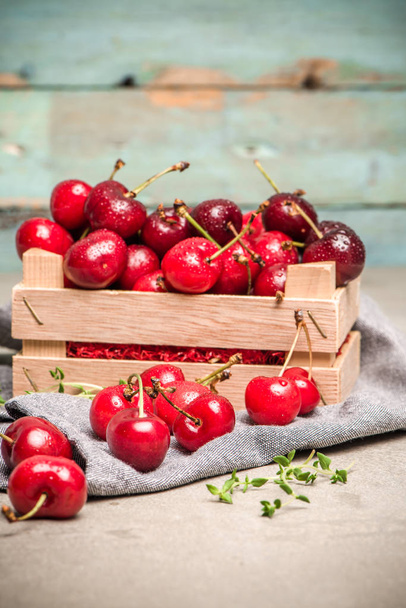 Red ripe cherries in small wooden box - 写真・画像