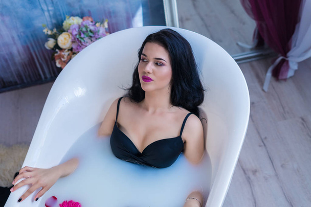 Sexy donna bruna rilassante nel bagno di latte caldo con fiori
 - Foto, immagini