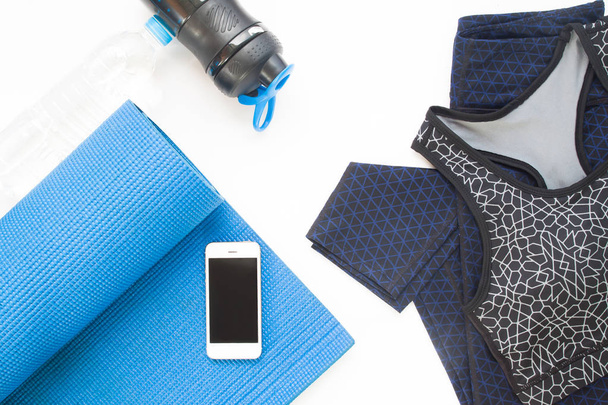 Вид сверху на мобильное устройство, коврик для йоги, одежду для йоги и бот
 - Фото, изображение