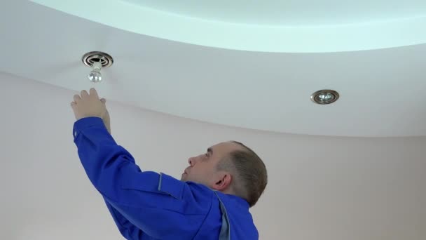 Young electrician man install or replace halogen spot light lamp into ceiling - Footage, Video