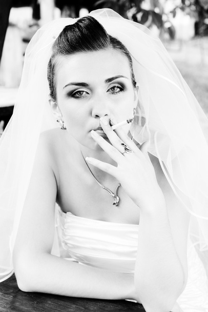 bruid in sluier roken van een sigaret - Foto, afbeelding