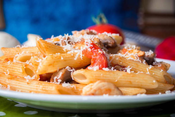 Massa Penne com cogumelos, frango, tomate e queijo parmesa
 - Foto, Imagem
