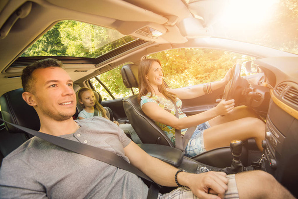 família de três desfrutando na condução de um carro
 - Foto, Imagem