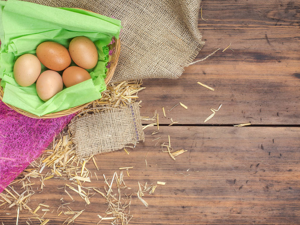 Rural eco background with brown chicken eggs, a piece of burlap and straw on the background of old wooden planks. The view from the top. Creative background for Easter cards - Fotografie, Obrázek