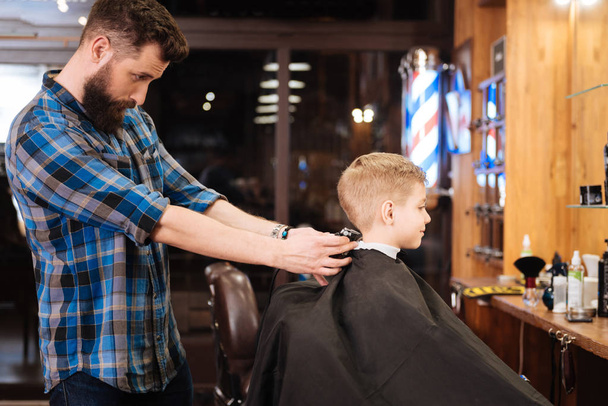 experienced hairdresser doing the haircut to boy - Foto, Imagen