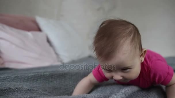 Happy baby girl crawling on bed - Filmati, video