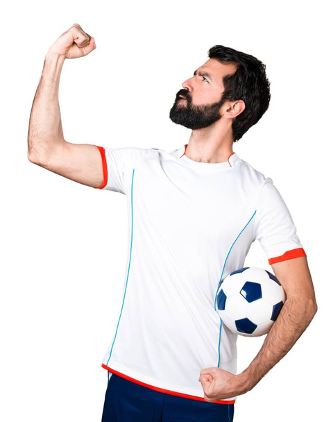 Τυχερός ποδοσφαιριστής κρατώντας μια μπάλα ποδοσφαίρου - Φωτογραφία, εικόνα