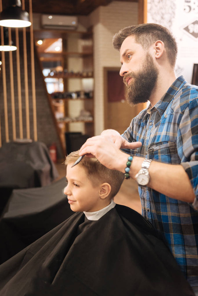 Serious male barber working with a young boy - Fotografie, Obrázek