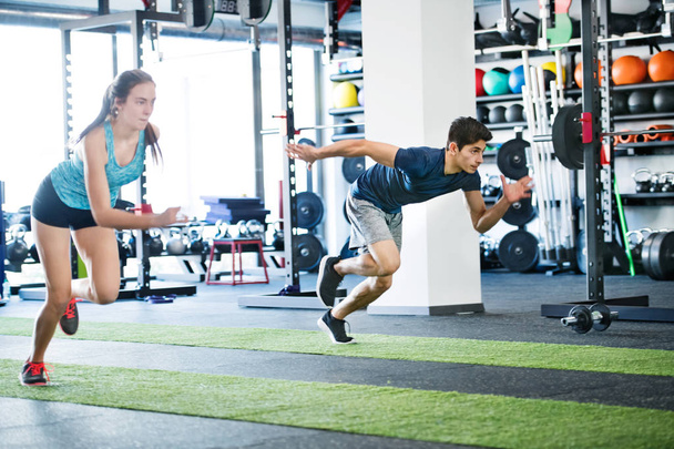 Young fit couple in gym fast running. - Foto, afbeelding