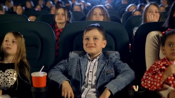 Niñas y niños viendo una película y comiendo palomitas de maíz en el cine
 - Imágenes, Vídeo