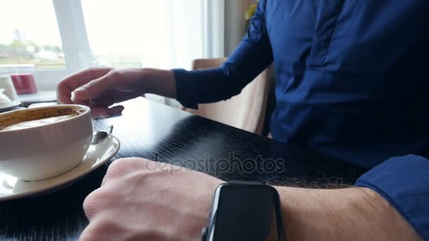 A cronologia do jovem no smartwatch a beber café. Sem rosto. Close-up
. - Filmagem, Vídeo