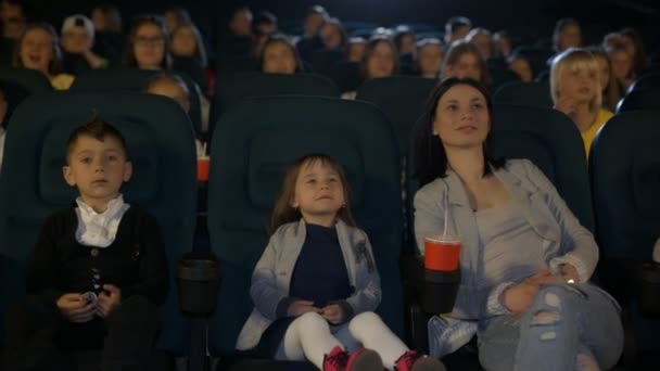 Een vrouw die kijken naar een film in de bioscoop met kleine dochter en vrienden. - Video