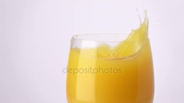 Slice of Orange Falling into a Glass of Orange Juice. - Imágenes, Vídeo