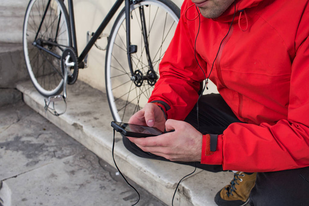 close up picture of cellphone in hands and black bicycle on background - Photo, image
