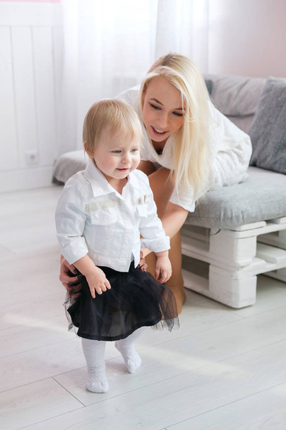 Adorable baby boy making first steps with mother at living room - Foto, Imagem