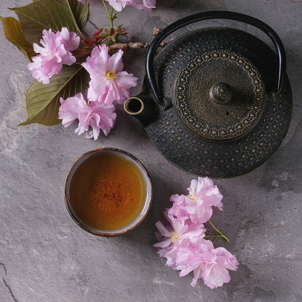 Teáskanna és a csésze tea a virág ág - Fotó, kép