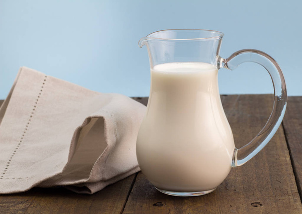 Plnotučné mléko ve skleněné konvici na dřevěný stůl - Fotografie, Obrázek