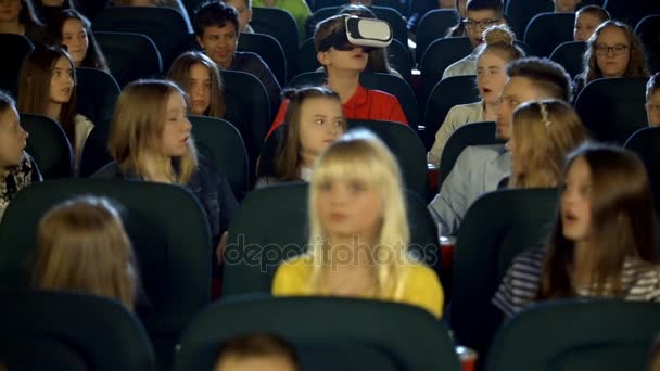 Niños pequeños adolescentes en el cine viendo a un niño con gafas de realidad virtual
. - Metraje, vídeo