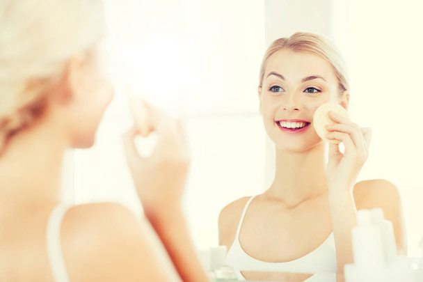 jeune femme lavage visage avec éponge à la salle de bain
 - Photo, image
