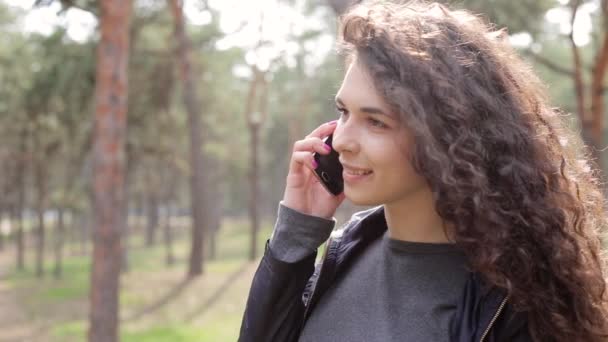Woman using mobile in park - Кадри, відео