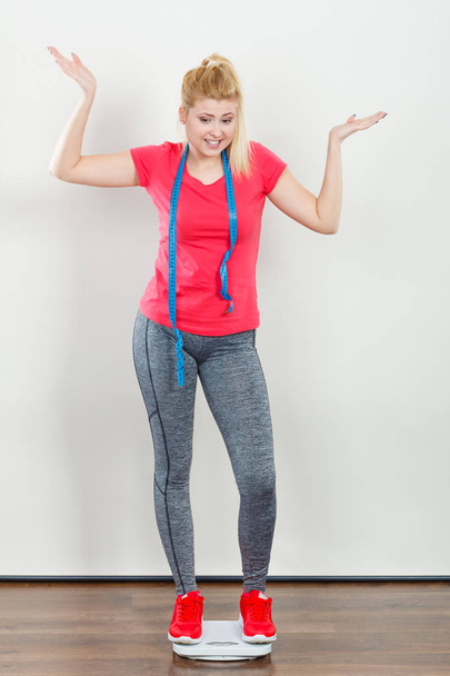 Woman wearing sportswear standing on weight machine - Zdjęcie, obraz