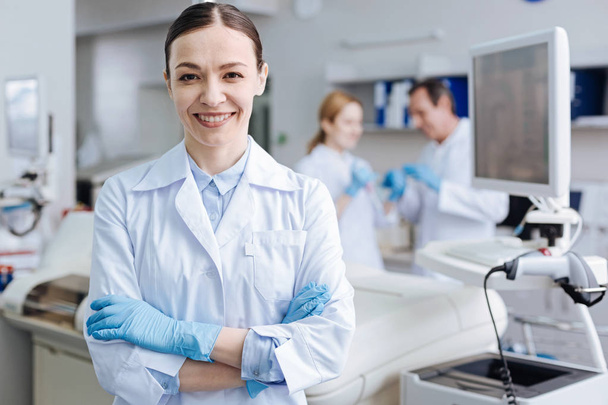 Positive delighted female lab assistant smiling on camera - Foto, Imagen